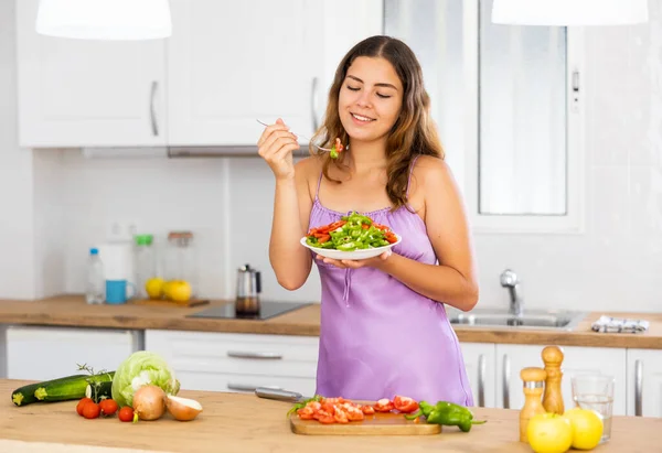 笑顔の主婦が自宅のテーブルで野菜サラダを食べる姿 — ストック写真