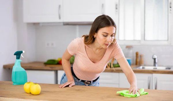 Konzentrierte Frau Freizeitkleidung Putzt Arbeitsplatte Küche Mit Lappen Und Spülmittel — Stockfoto