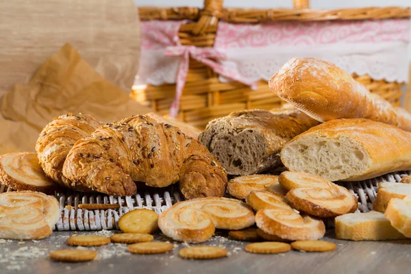 新烘焙的小麦和谷物面包 羊角面包和不同的饼干 背景为柳条形 — 图库照片