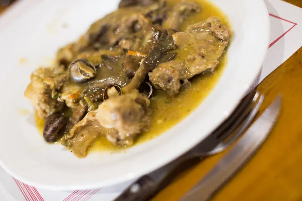 portion of cooked rabbit meat with snails served with tasty sauce