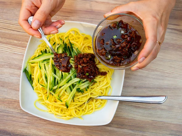 Female Hands Pouring Cucumber Noodles Mushroom Sauce Chinese Cuisine — Stock Photo, Image