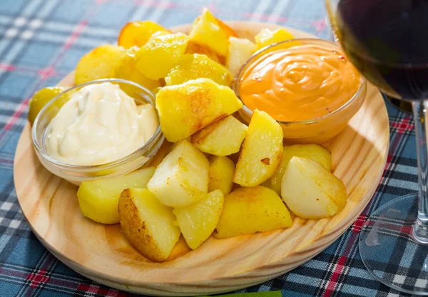 Spanish cuisine. Delicious deep fried potatoes Patatas bravas with two sauces on wooden board