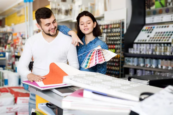 快乐的年轻夫妇在油漆供应商店检查各种色彩方案 — 图库照片
