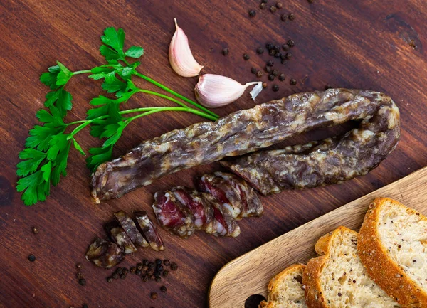 干猪肉香肠放在木桌上 配以欧芹 胡椒和大蒜 — 图库照片