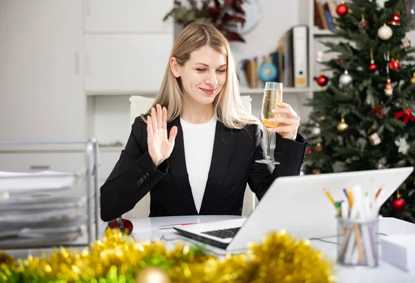 シャンパンのグラスを持つビジネス女性はオフィスでインターネット上でメリークリスマスを祝います — ストック写真