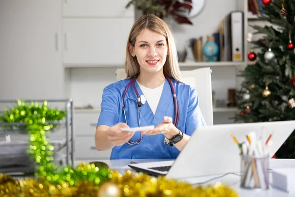 クリスマスの間にラップトップコンピュータを使用して医務室で働く正の女性医師 — ストック写真