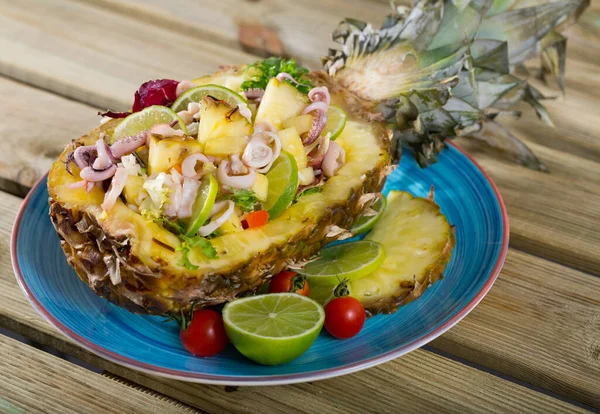 Exotic salad with calamari, pineapple and lime served in pineapple cut in half with dressing of pineapple juice, olive oil, lime and chili pepper
