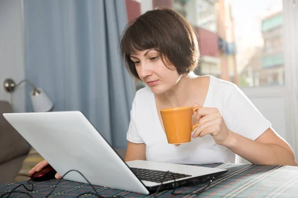 Relaxed brunette woman working at laptop at home