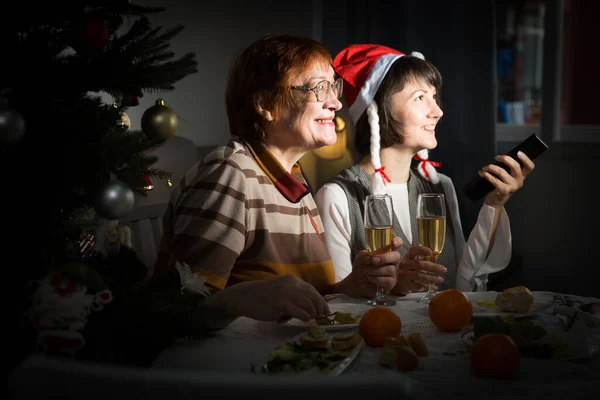 Mulheres Sorridentes Assistindo Programa Natal Sentado Mesa Com Copos Vinho — Fotografia de Stock