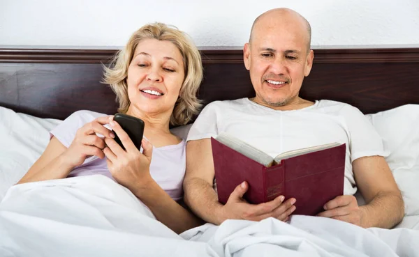Smiling Mature Boyfriend Girlfriend Lying Bed Socialising Mobile Phones — Stock fotografie