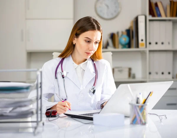 Médica Feminina Positiva Com Estetoscópio Sentado Mesa Trabalhando Laptop Consultório — Fotografia de Stock