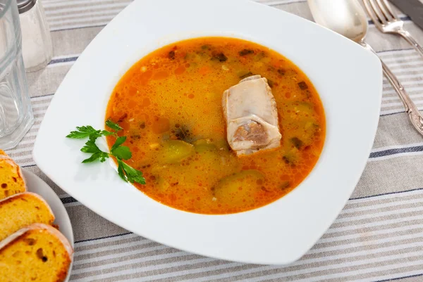 Popular dish of Russian cuisine is Pickle soup with meat, cooked on the basis of pickled cucumbers and pearl barley or rice, ..decorated with a sprig of parsley on top. Served with bread
