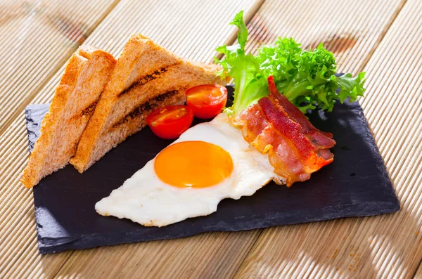 Νόστιμο Πρωινό Τηγανητά Αυγά Μπέικον Ψωμί Και Λαχανικά Γαρνιτούρα Μαύρο — Φωτογραφία Αρχείου