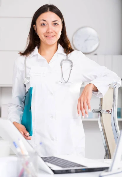 Νεαρή Γυναίκα Γιατρός Λευκή Στολή Κρατώντας Πρόχειρο Στο Γραφείο Κλινικές — Φωτογραφία Αρχείου
