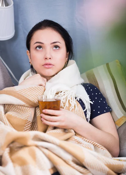 女の子飲む暖かいお茶包装で毛布オンソファ — ストック写真