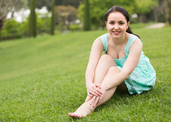 Uśmiechnięta Młoda Amerykańska Brunetka Sukience Siedząca Trawie Świeżym Powietrzu — Zdjęcie stockowe