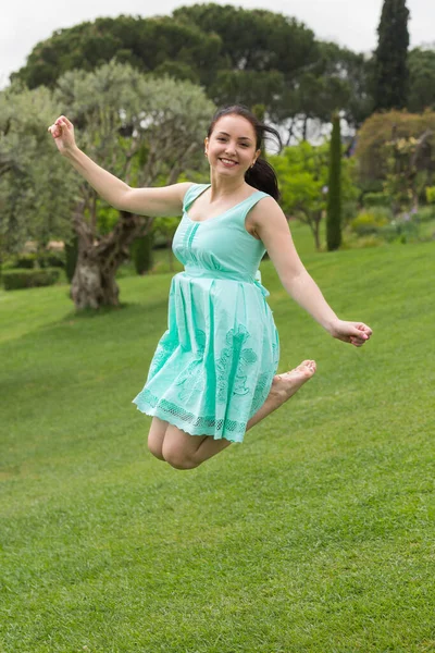 快乐的年轻英国黑发女子在公园里跳着衣服 — 图库照片