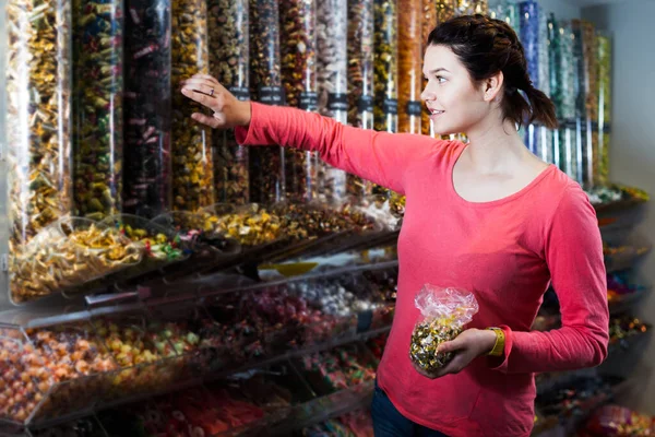 가게에서 선물로 사탕을 고르는 긍정적 소녀의 — 스톡 사진