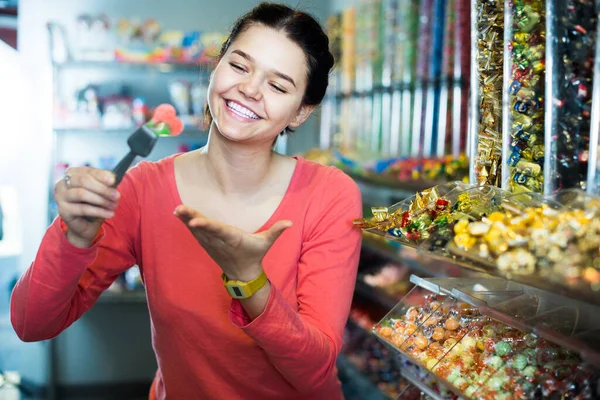 一个微笑的女孩在糖果店里看着鲜亮可口的果酱 — 图库照片