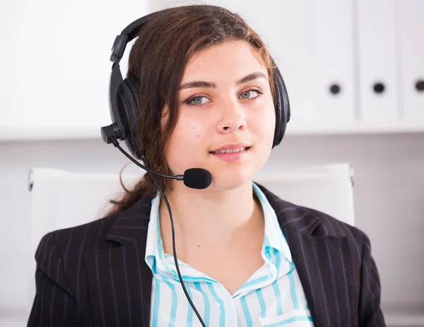 若いディスパッチャの女性はオフィスでコンピュータと話してヘッドセットで働いています — ストック写真