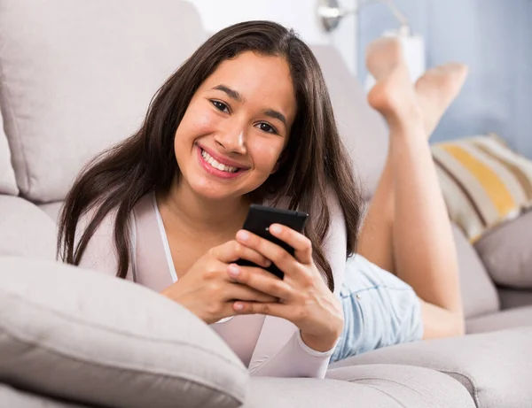 Lächelnde Junge Frau Träumt Mit Handy Auf Sofa Drinnen — Stockfoto