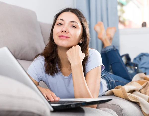 若いです女性学生使用ノートパソコンとリラックスしたソファに自宅 — ストック写真