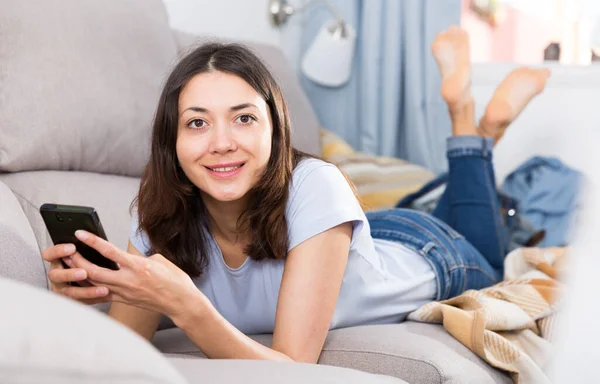 Mujer Joven Sonriente Usando Teléfono Inteligente Tumbado Sofá Interior Casa — Foto de Stock