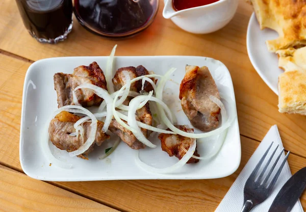 stock image Traditional georgian dish shish kebab or shashlik, grilled pork meat served with pickled onion