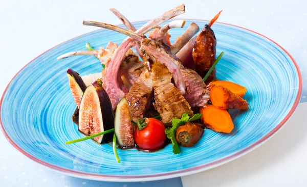 Appetizing baked lamb ribs with garnish of vegetables and fresh figs served with demi-glace and greens