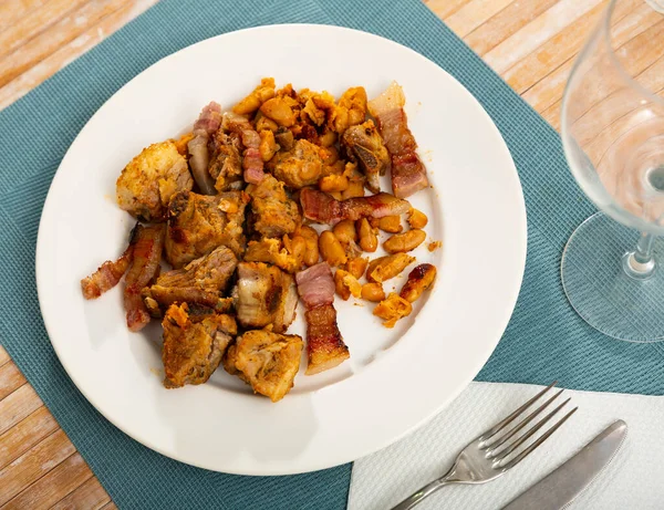 白盘上烤猪肉和炖豆的美味肉食 — 图库照片