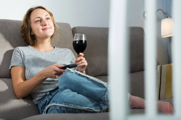 Smiling Young Woman Glass Wine Remote Sitting Couch Home Watching — Zdjęcie stockowe