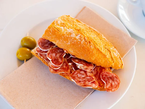 Appetizing Spanish breakfast-sandwich with delicious delicaty dried sausage Fuet