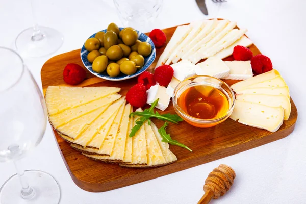 チーズプレート ラズベリーチーズの品揃え セラミックプレート上の緑のオリーブと蜂蜜 — ストック写真