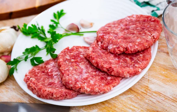 Cooking ingredients, raw burger cutlets on wooden board
