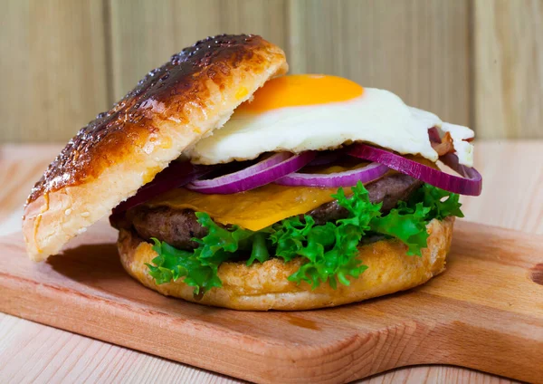 Smaczny Hamburger Jajkiem Smażonym Wołowiną Cebulą Serem Sałatą — Zdjęcie stockowe