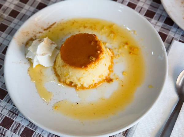 Image of tasty spanish dessert flan con nata served with caramel crust at plate