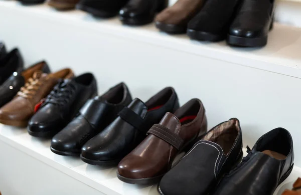 Row of leather boots for men in showroom of shoe store.