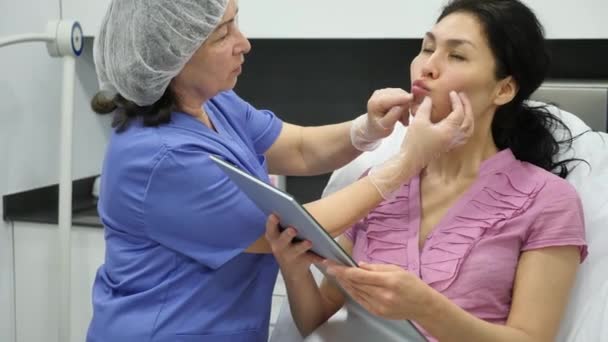 現代の審美的な医療事務所でアジアの女性患者のための今後の唇の整形手順を計画プロの高齢女性美容師 — ストック動画