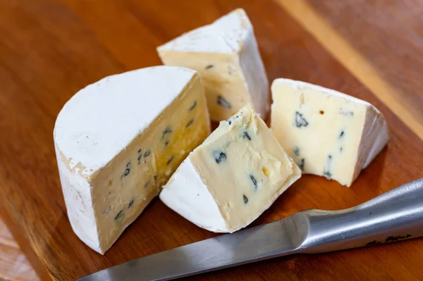 ナイフで木製のテーブルの上に高貴な青カビと職人豊かなクリーミーなチーズのスライス 人気の乳製品料理 — ストック写真