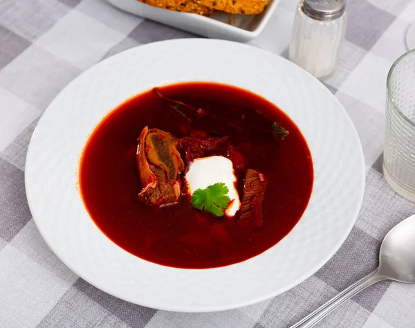 ロシアのビートルートスープ骨肉で調理伝統的に緑で飾られたサワークリームを提供しています — ストック写真