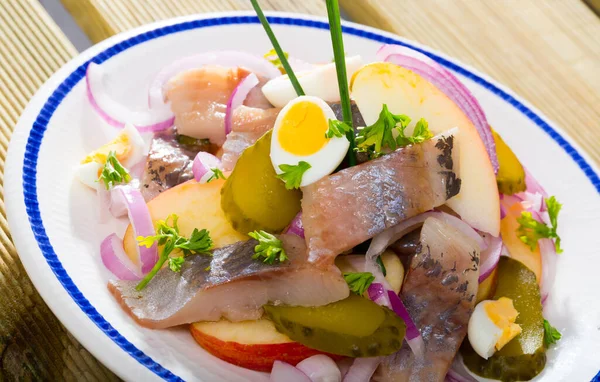 stock image Slightly salted herring with sliced apples, red onion, pickles, quail egg - traditional dish of Norwegian cuisine