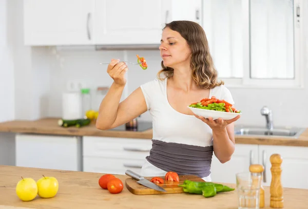 Genç Pozitif Kadın Yemek Pişirdikten Sonra Mutfakta Salata Yiyor — Stok fotoğraf