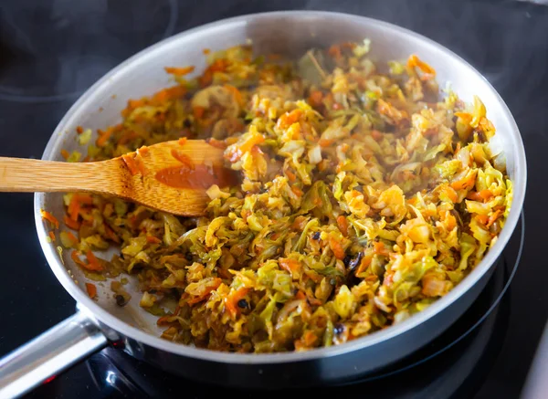 stock image Closeup of braised white cabbage, stewed with carrots and onions in a pan on a kitchen stove