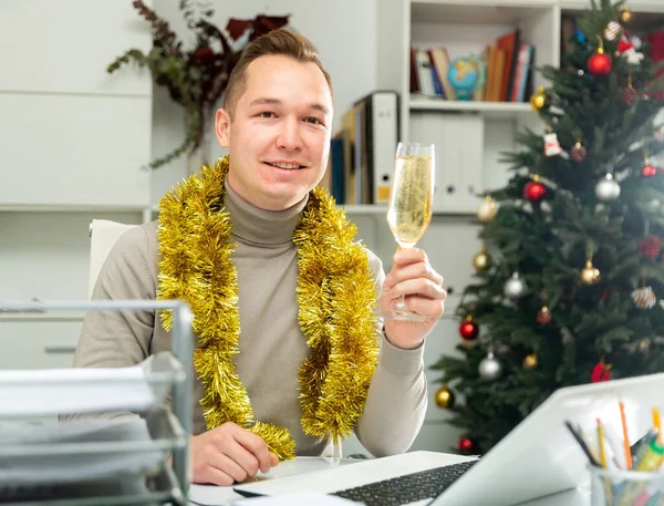 新年を祝う笑顔の男のオフィスマネージャーシャンパンのグラスとテーブルに座って — ストック写真