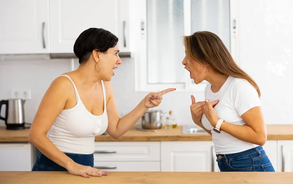 2人の怒っ不満若いヒスパニック系の女性は自宅のキッチンで口論しながら感情的にジェスチャー 姉妹関係の問題 — ストック写真