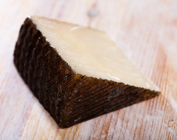 木质背景下质地坚实的西班牙老羊乳酪片 — 图库照片