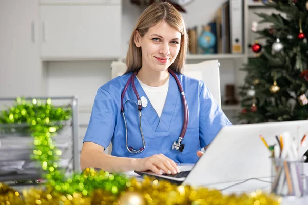 Jovem Mulher Médica Caucasiana Sentada Mesa Escritório Decorado Durante Natal — Fotografia de Stock