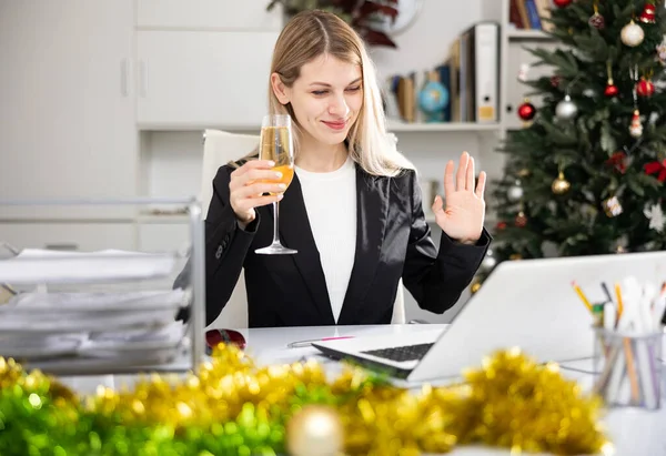 크리스마스 사무실에서 노트북으로 비디오 통화를 여성을 샴페인을 마십니다 — 스톡 사진