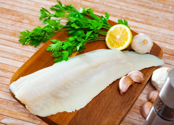 Tahta Zemin Üzerinde Sarımsak Yeşillikle Pişirmeden Önce Çiğ Balık Filetosu — Stok fotoğraf