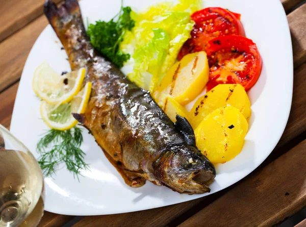 美味的整条鳟鱼 烤着土豆和西红柿 配上青菜 — 图库照片